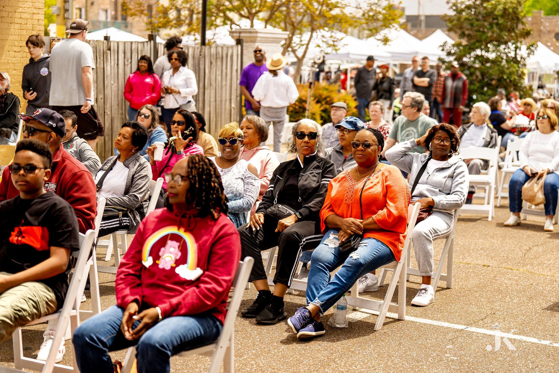 A large group of people are sitting in chairs outside.