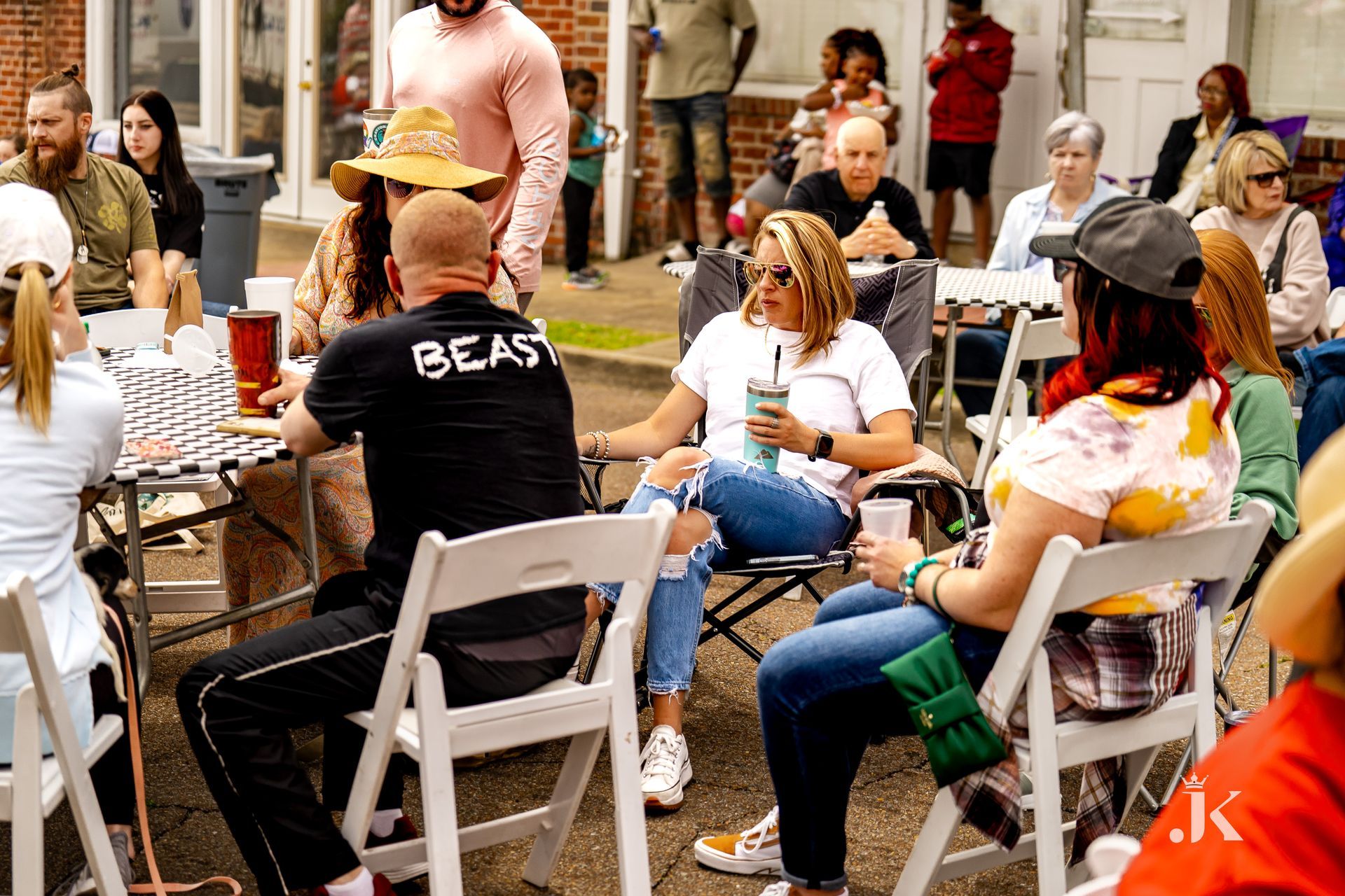 A group of people are sitting around a table and chairs.