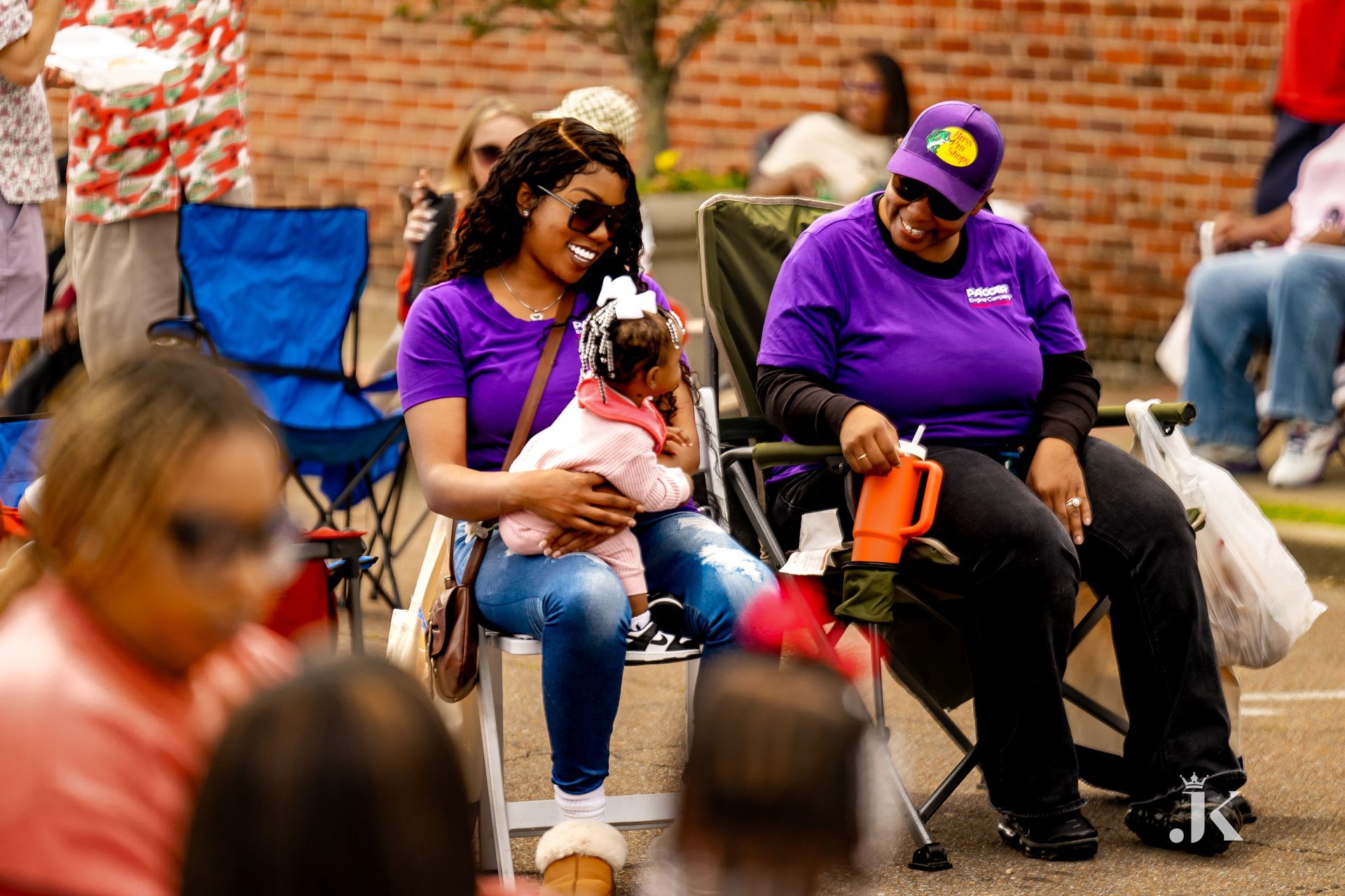 Two women are sitting in chairs holding a baby.