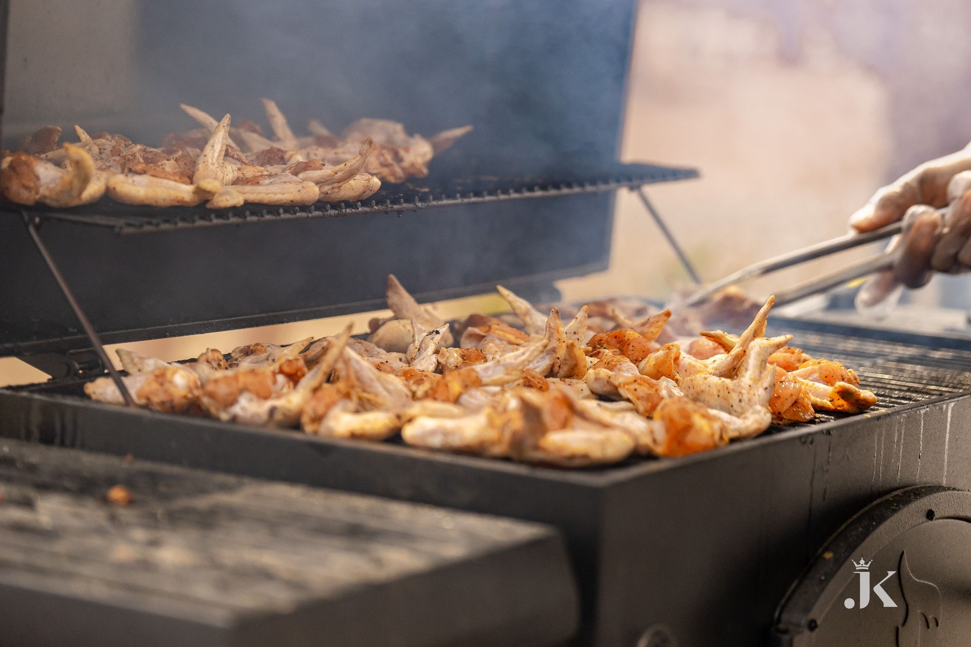 A person is grilling chicken wings on a grill.