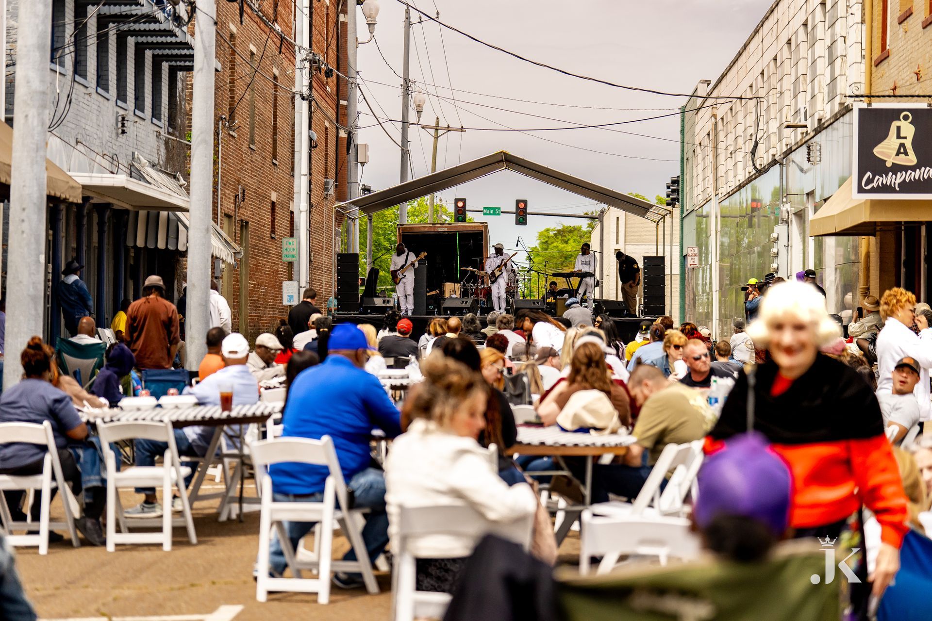 A crowd of people are sitting at tables and chairs in front of a stage.
