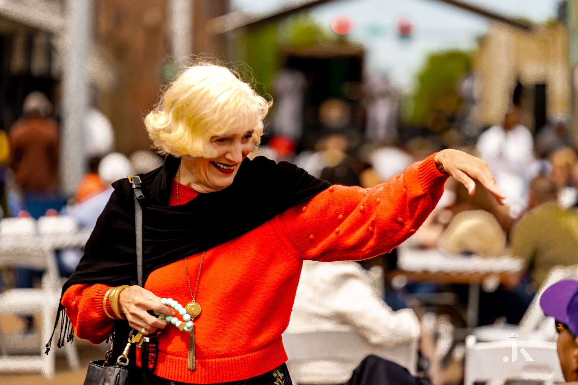 A woman in a red sweater and black scarf is dancing in front of a crowd.