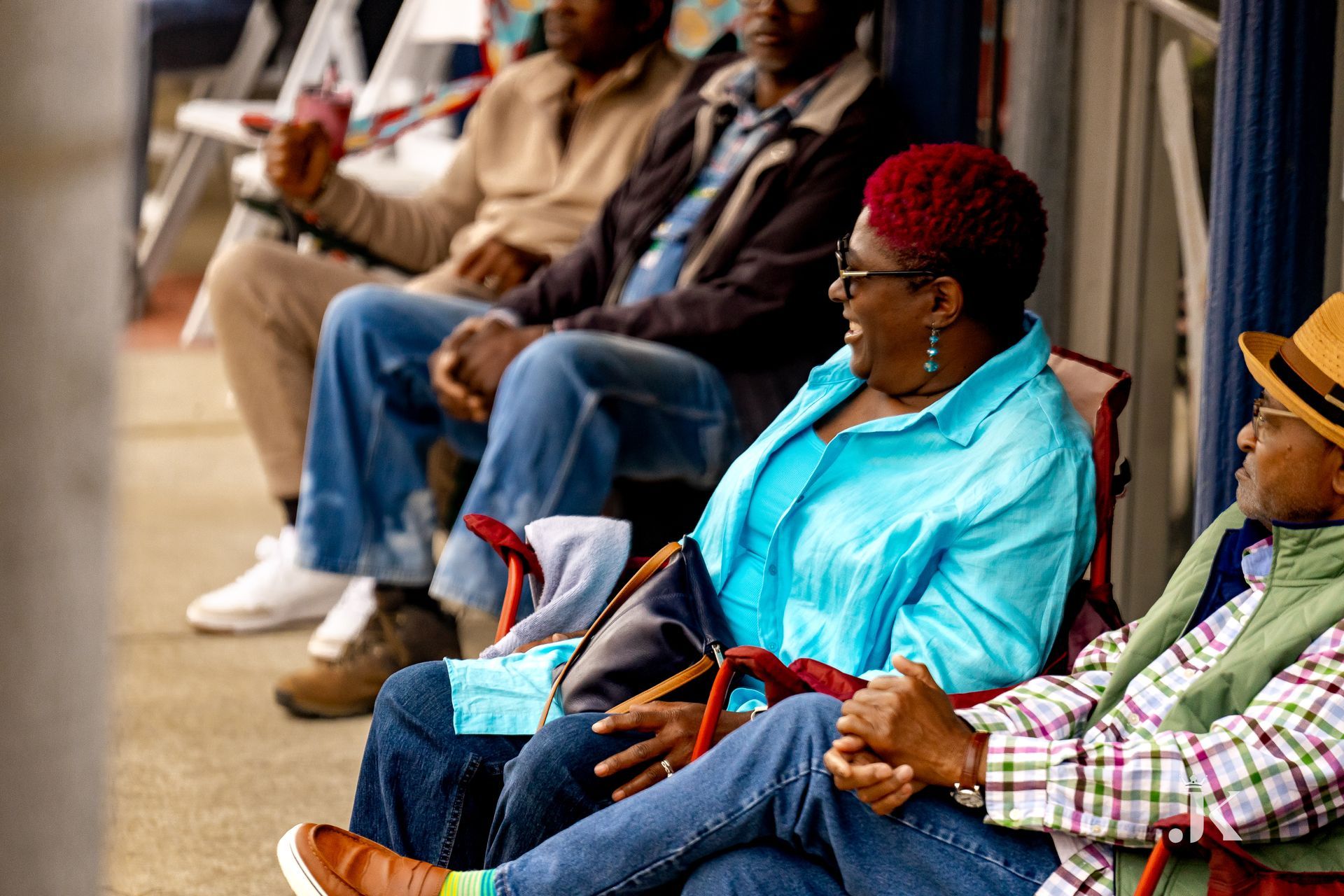 A group of people are sitting in chairs on the sidewalk.