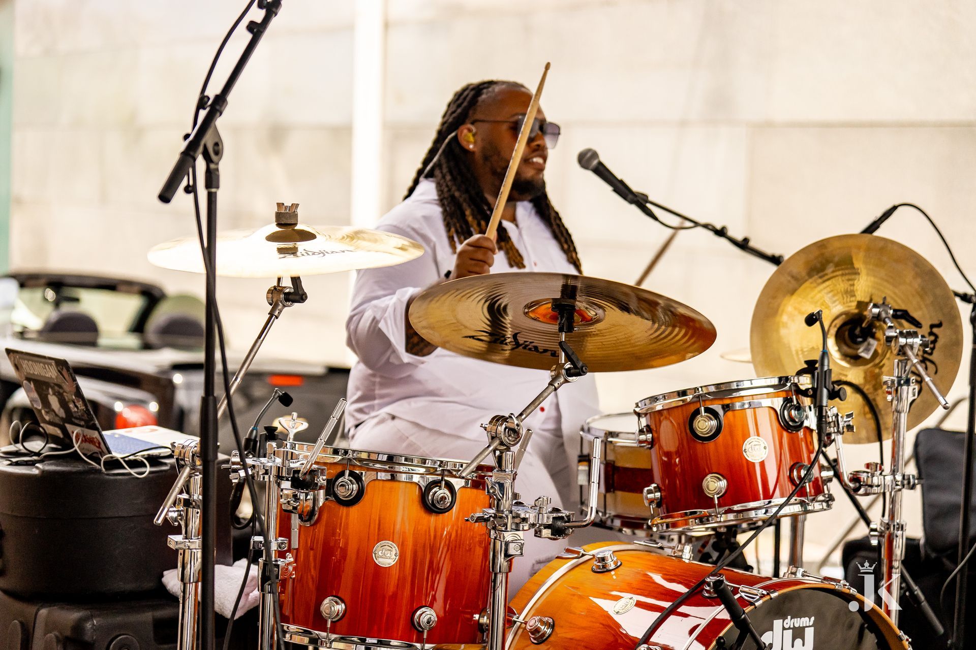 A man is playing drums on a stage in front of a microphone.