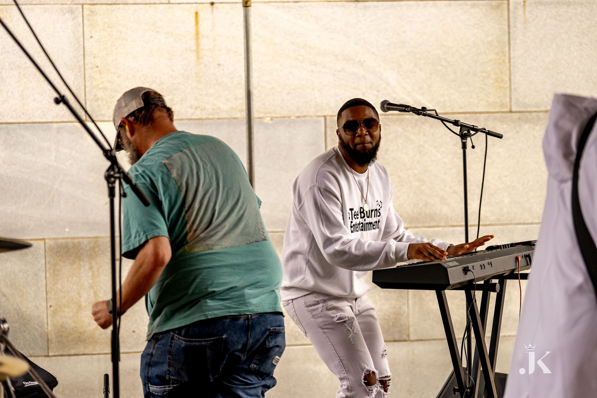 A man is playing a keyboard while another man stands behind him.