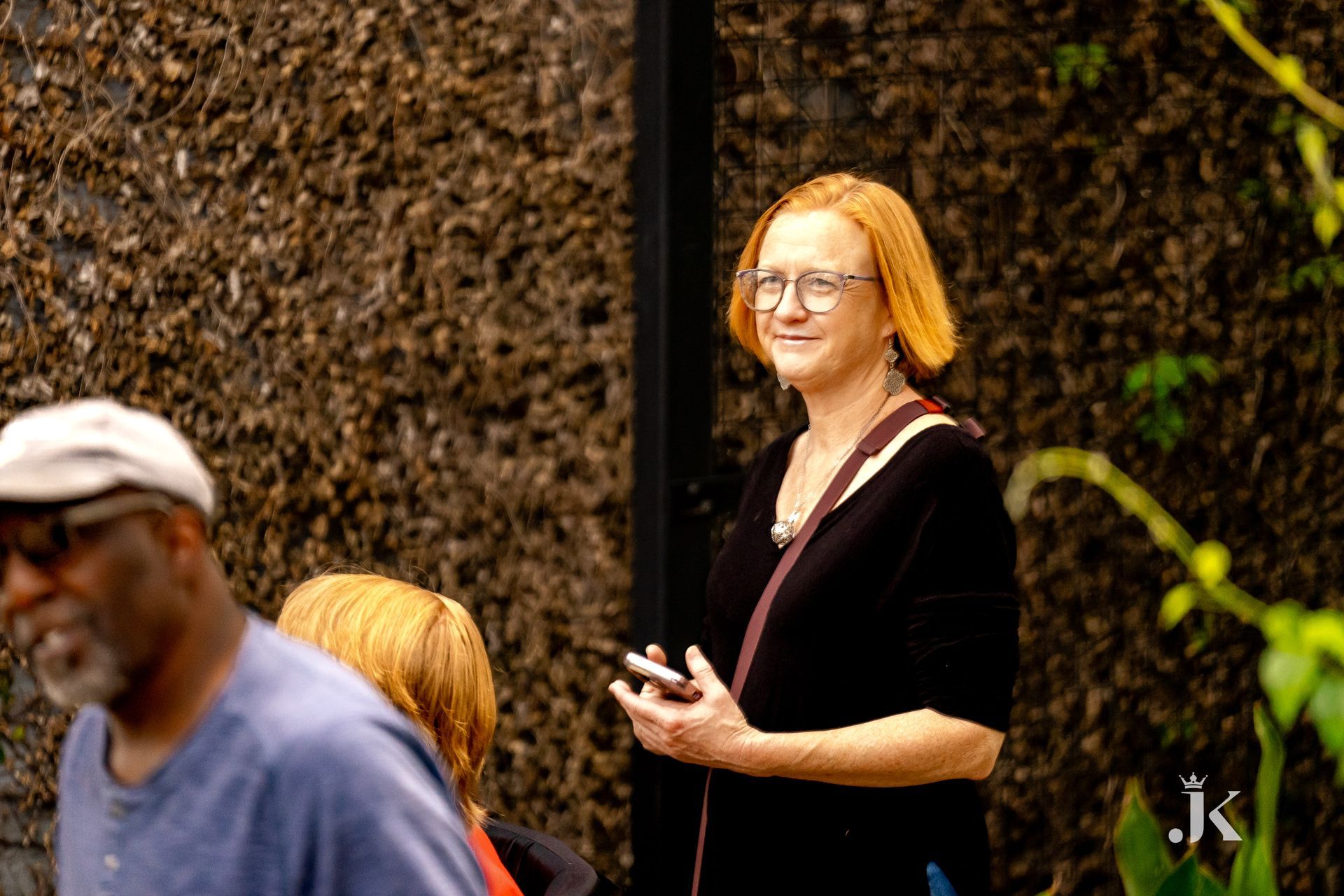 A woman with red hair is standing in front of a wall