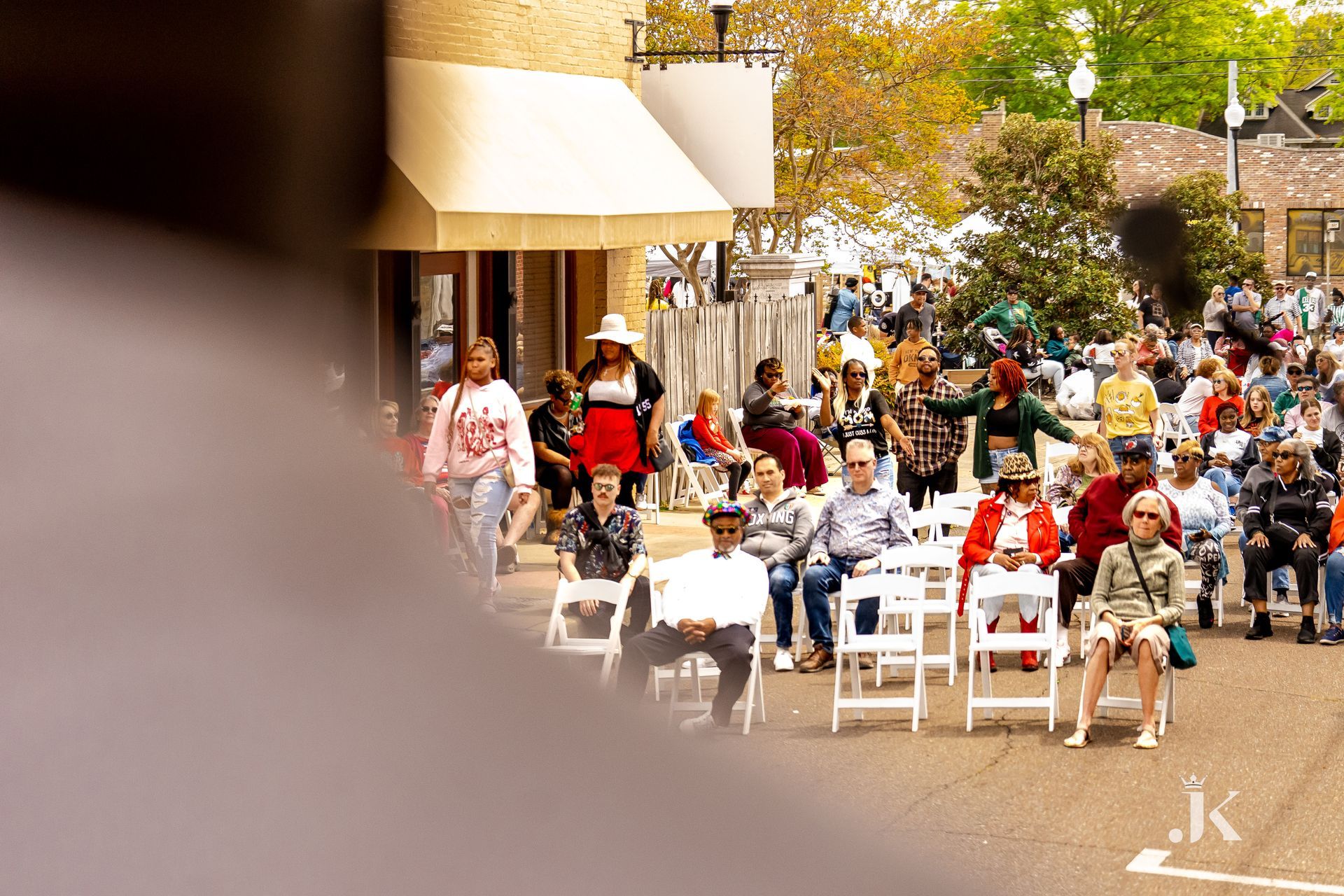 A crowd of people are sitting in chairs on a street.