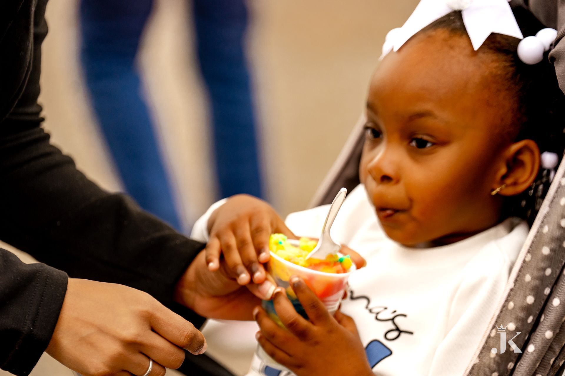 A little girl is sitting in a stroller eating from a cup