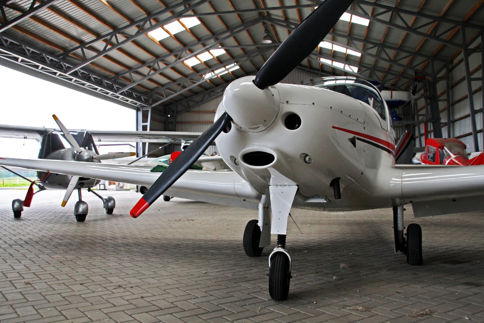 Several small planes are parked inside of a hangar