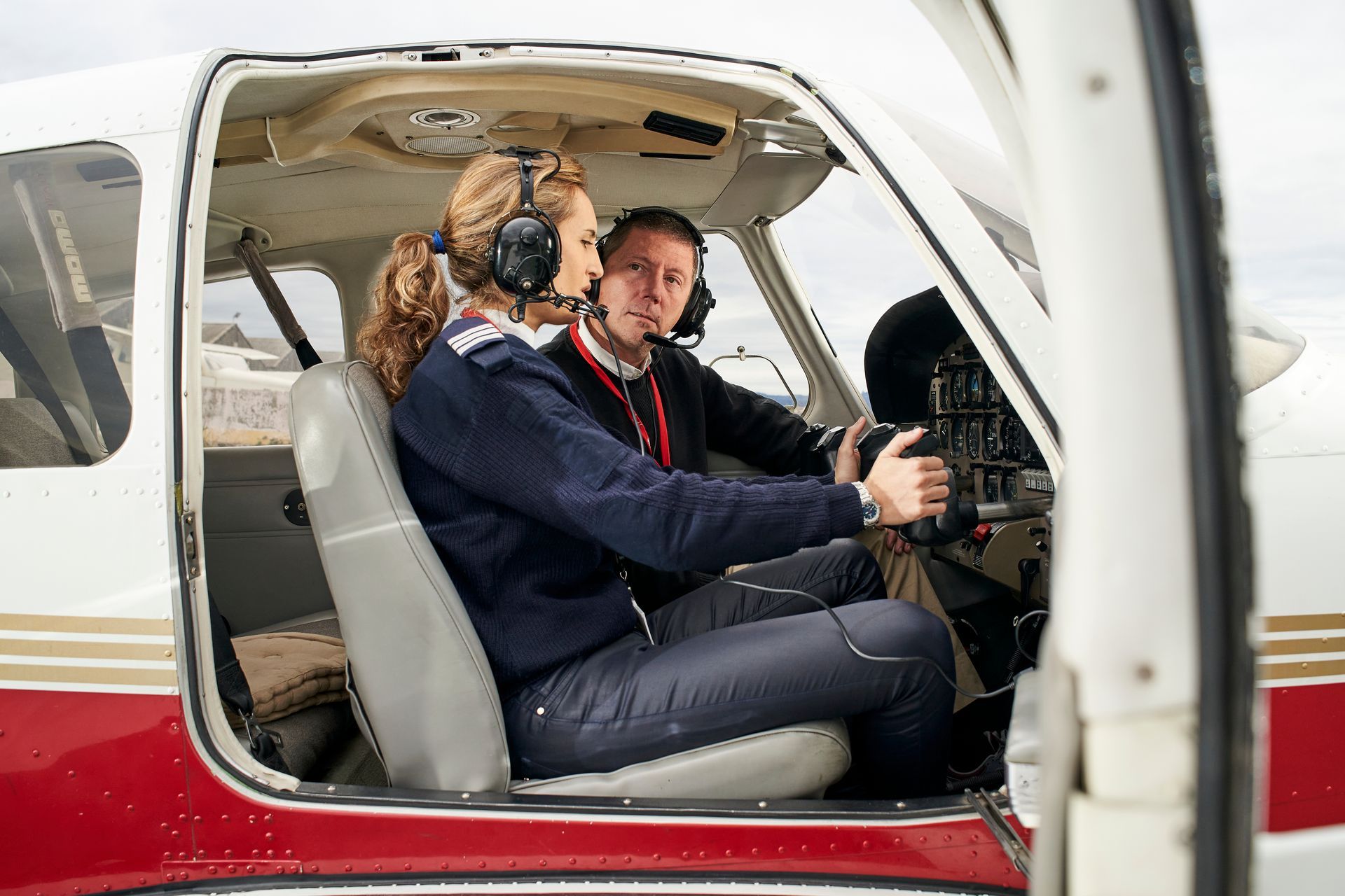 A man and a woman are sitting in the cockpit of an airplane.