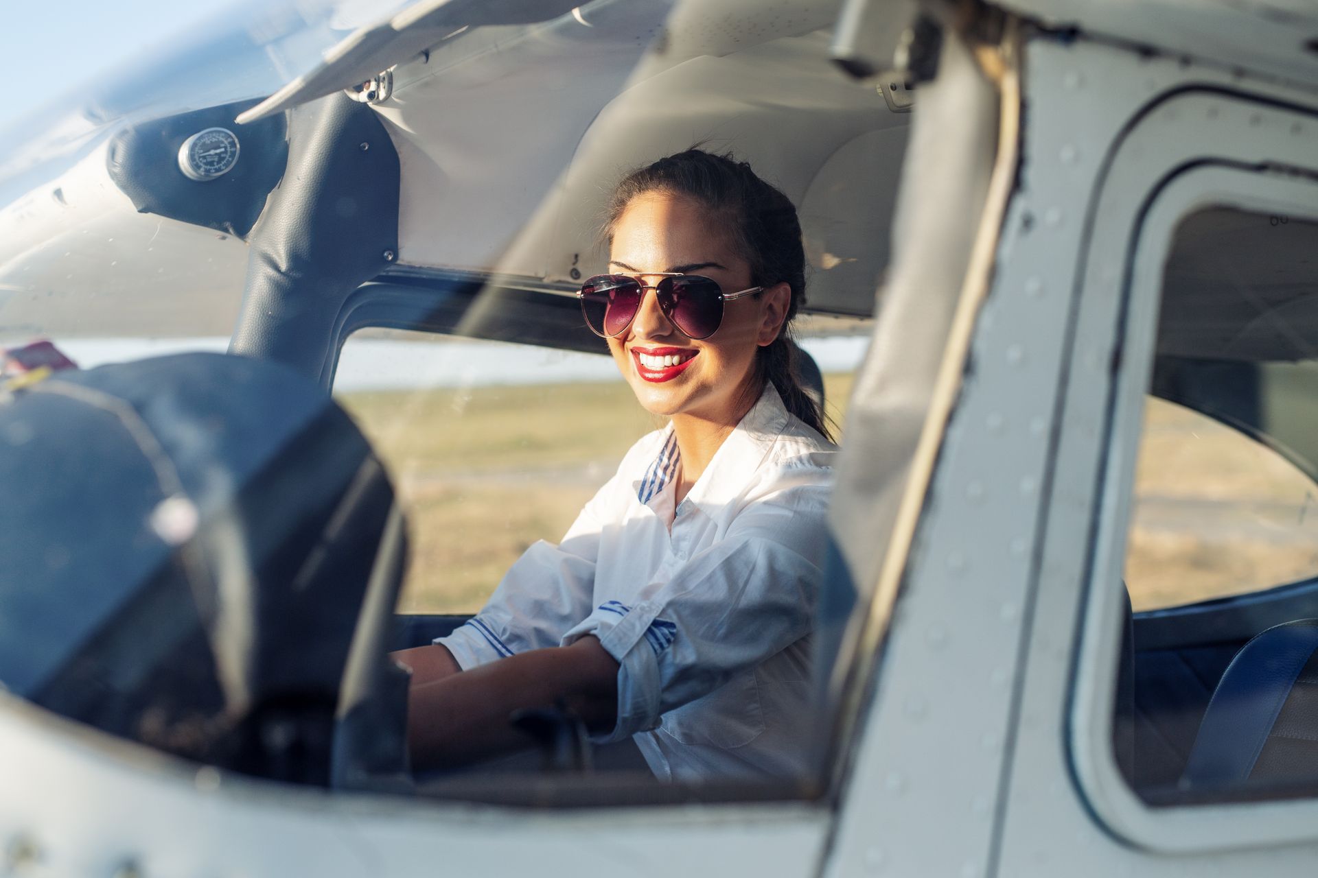 A woman is sitting in the cockpit of an airplane.