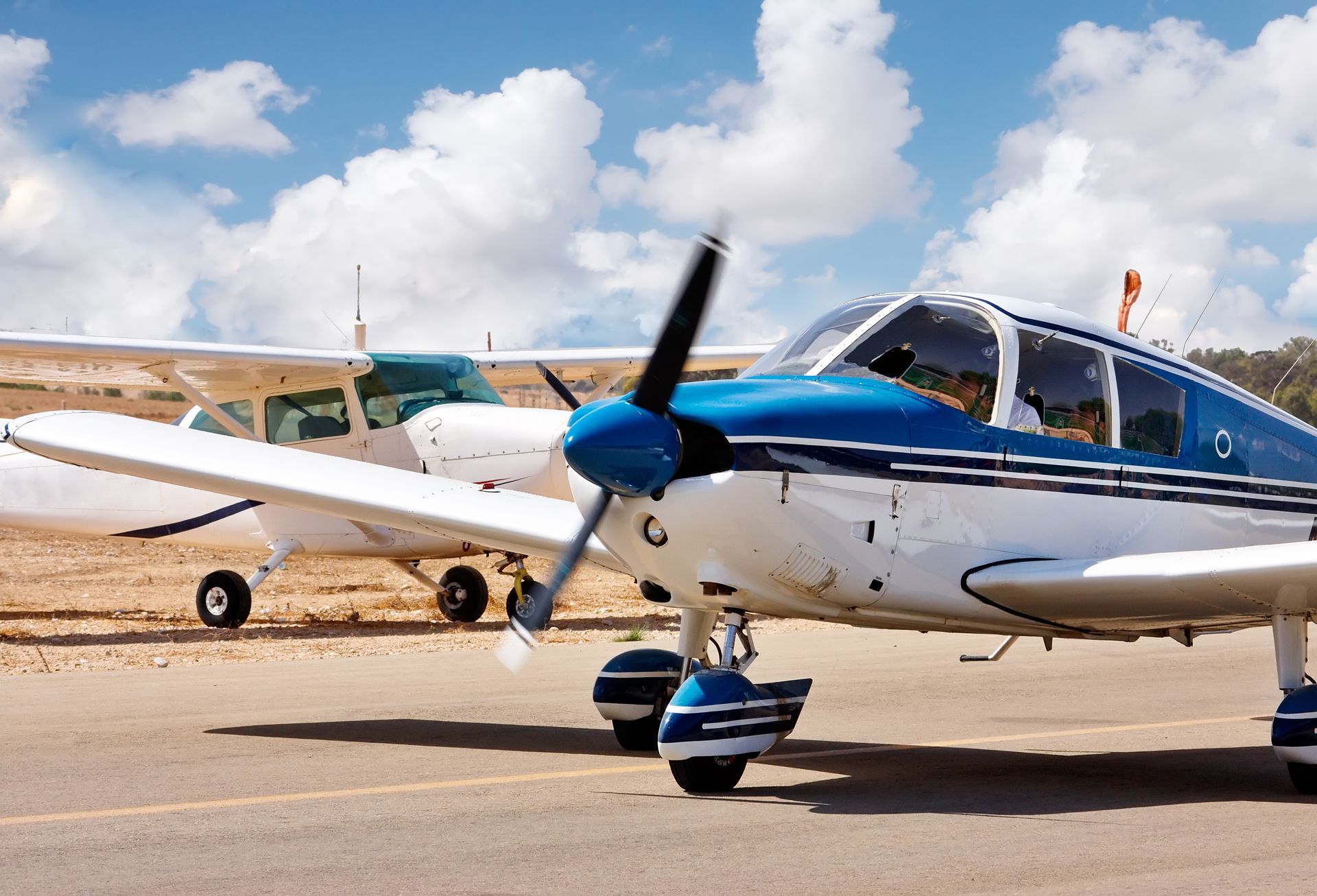 Two small planes are parked next to each other on a runway