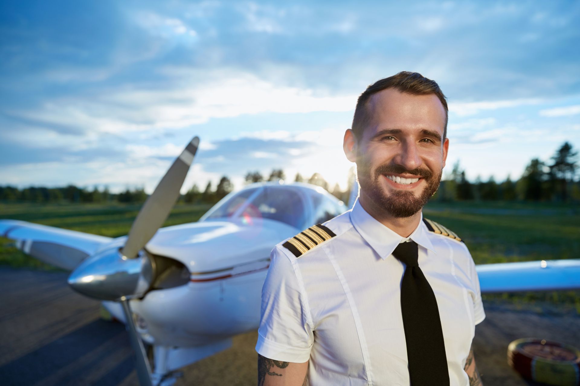 A pilot is standing in front of a small plane on a runway.