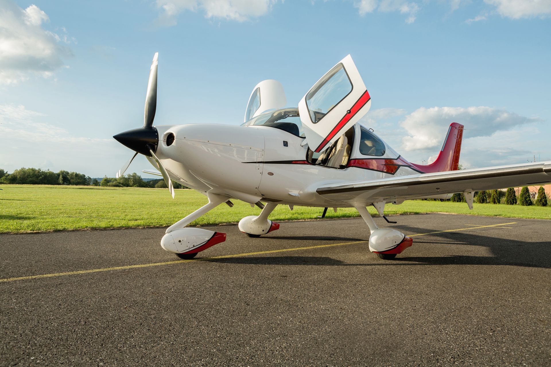 A small propeller plane is parked on the runway with its doors open.
