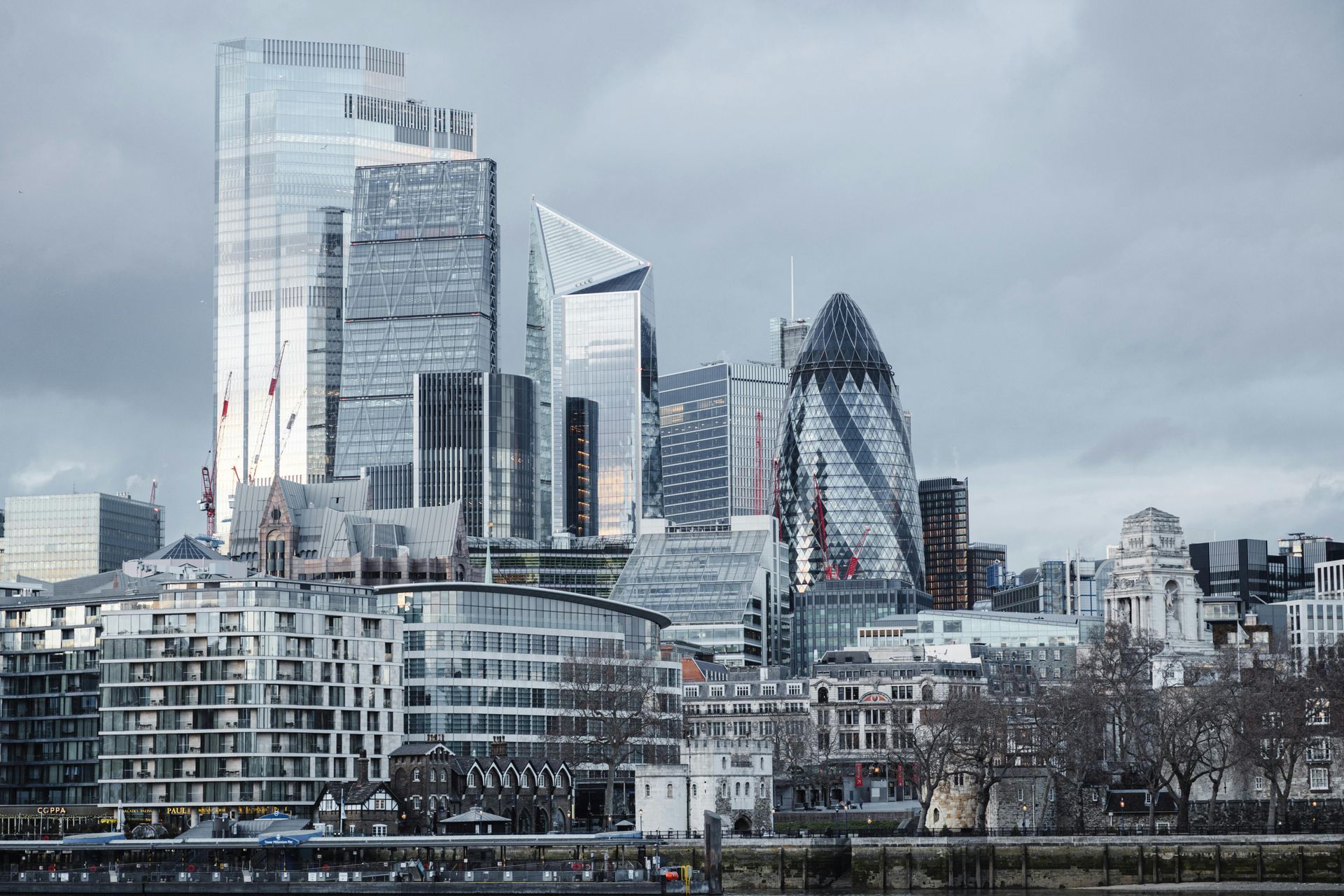 London skyline featuring the Gherkin and modern glass skyscrapers under a cloudy sky.