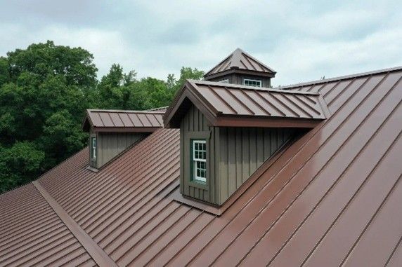 A brown roof featuring two windows and green foliage in the background.