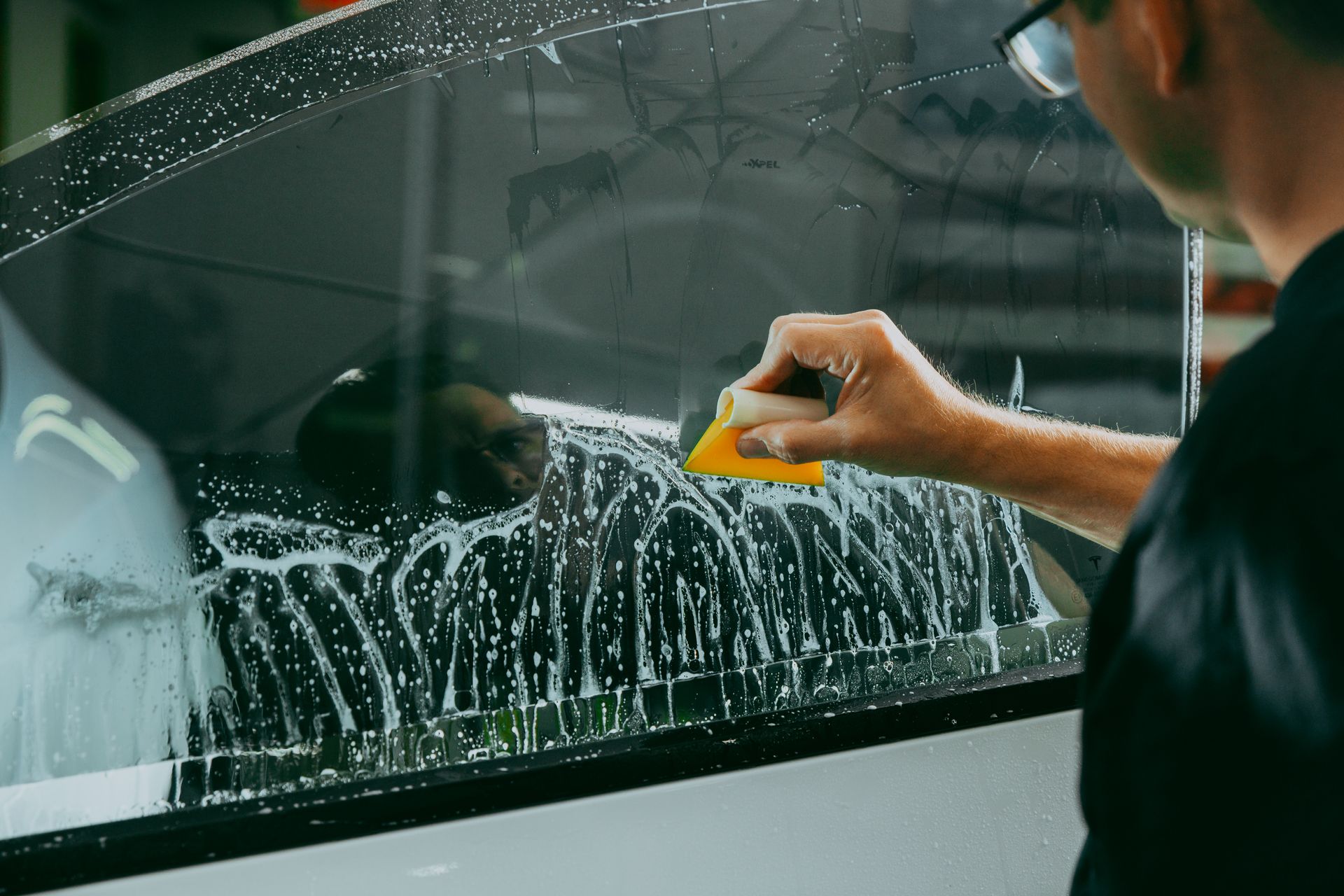 Window Tinting - A man is applying tinted glass to a window.
