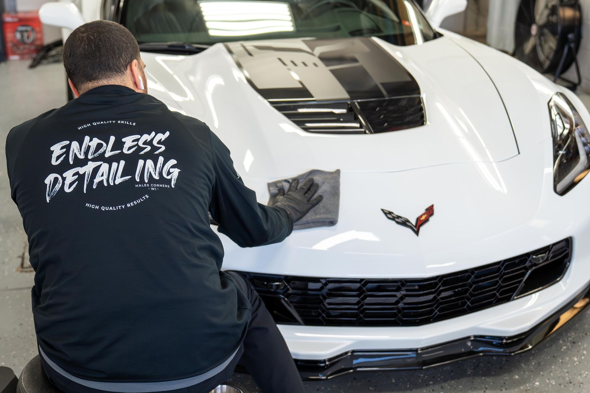 Exterior Detailing - A man is cleaning a white car with a cloth .