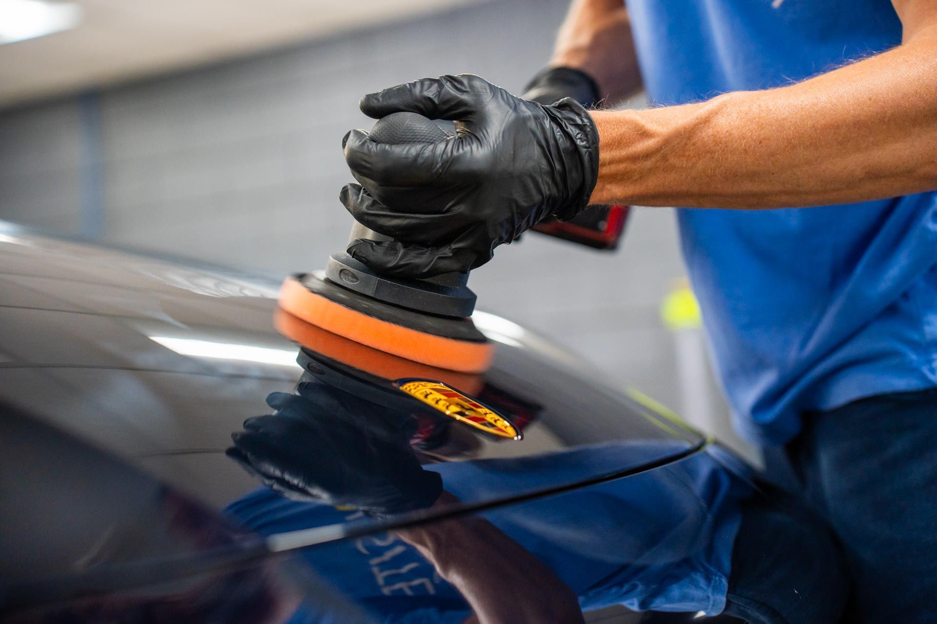 Paint Correction - A man is polishing the hood of a car with a buffing machine.