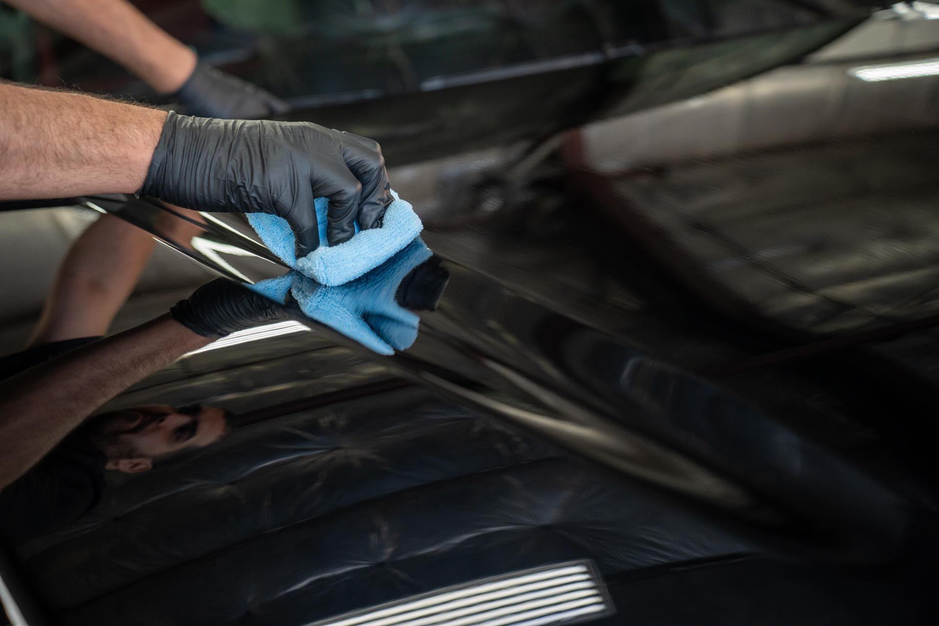 Ceramic Coating - A person is cleaning the windshield of a car with a cloth .