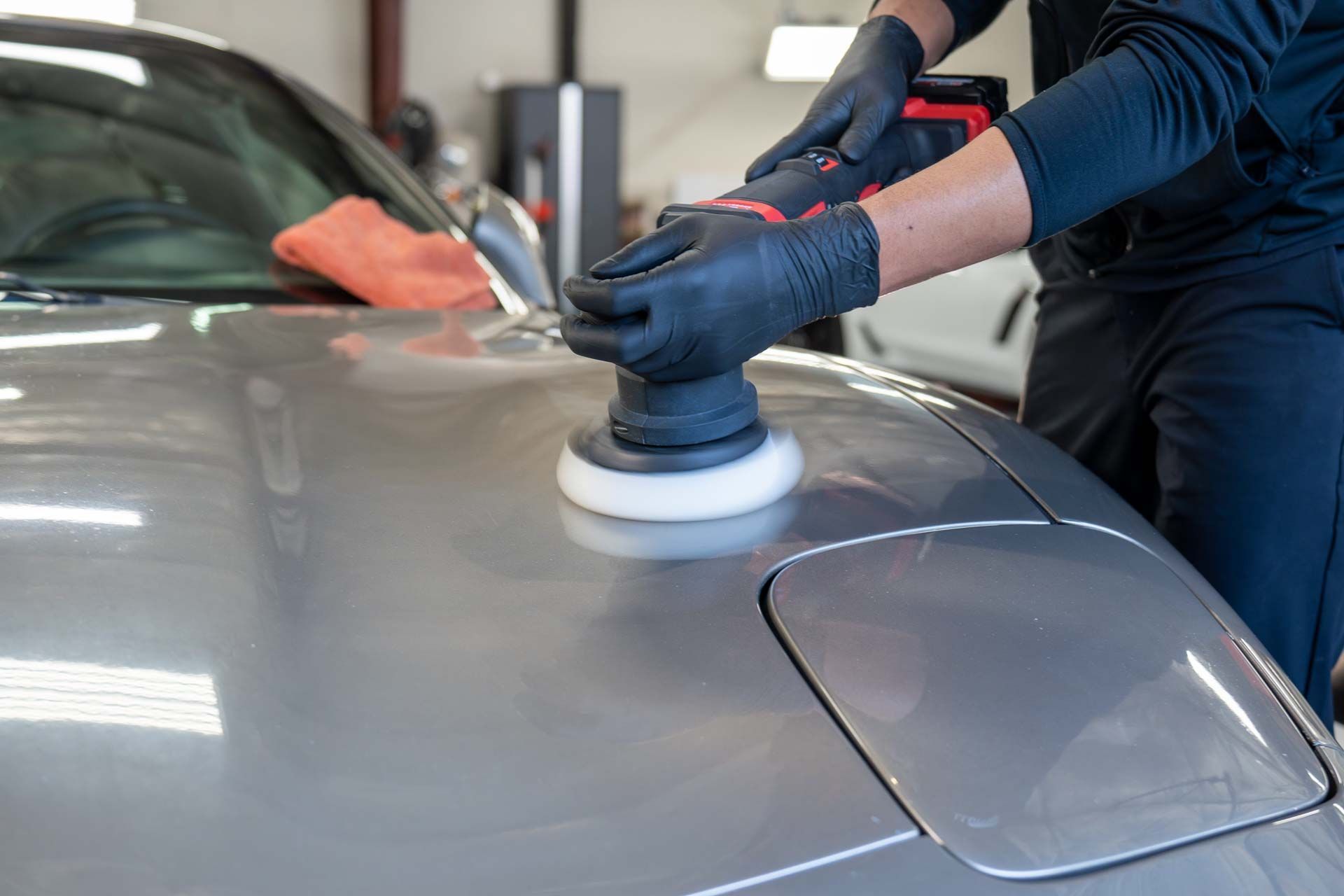 Paint Correction - A man is polishing the hood of a car with a machine in Cape Code, MA