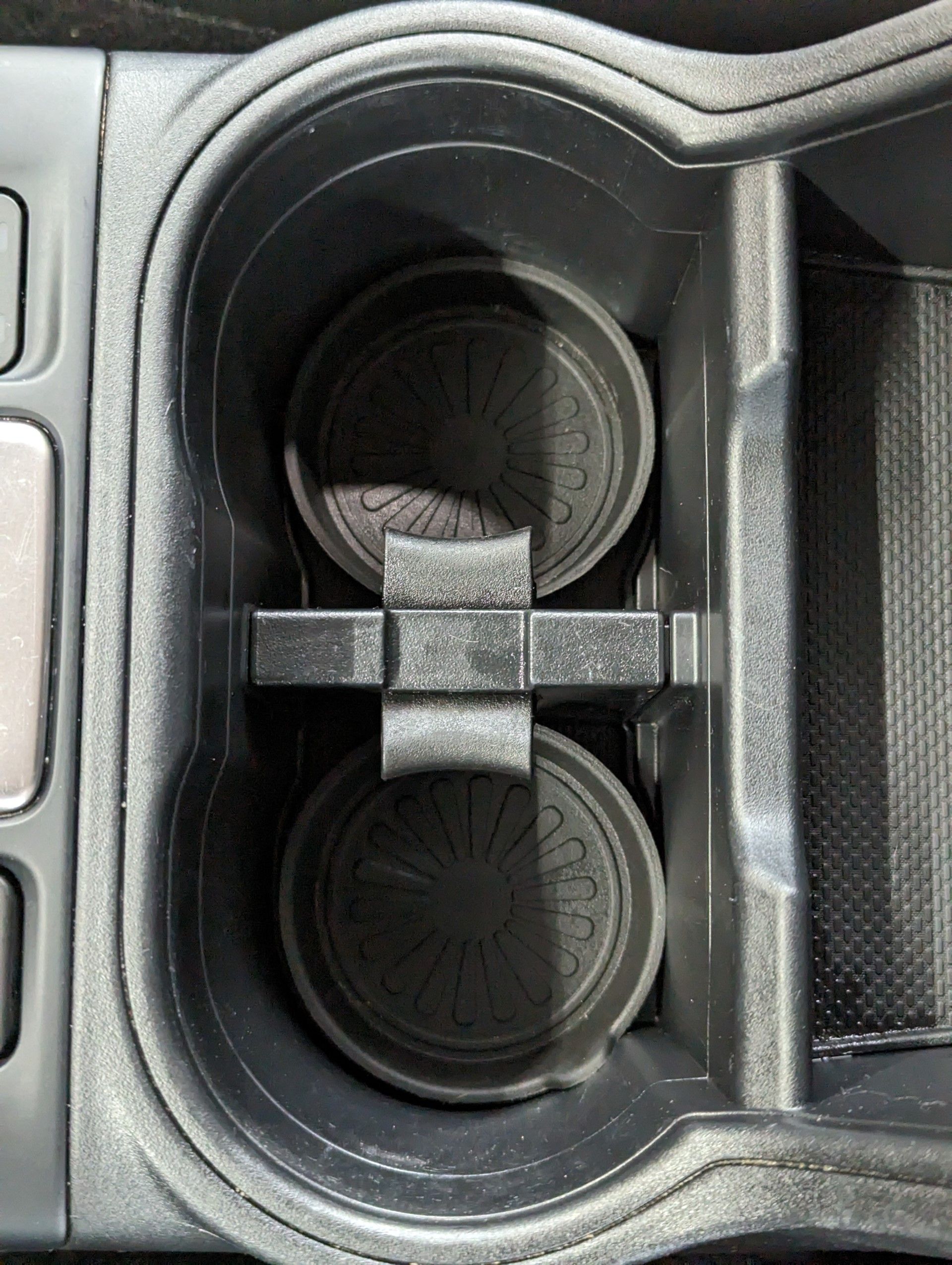 After Interior Detailing - A close up of a cup holder in a car with two cups in it .