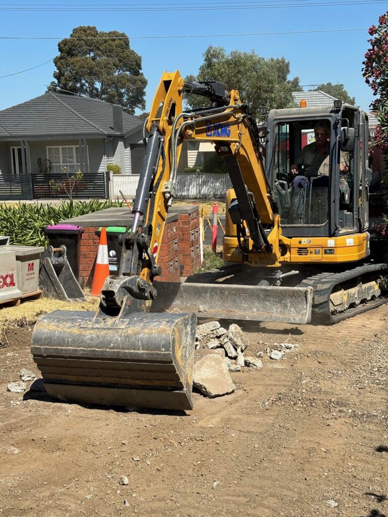 A yellow excavator is sitting on top of a dirt field.