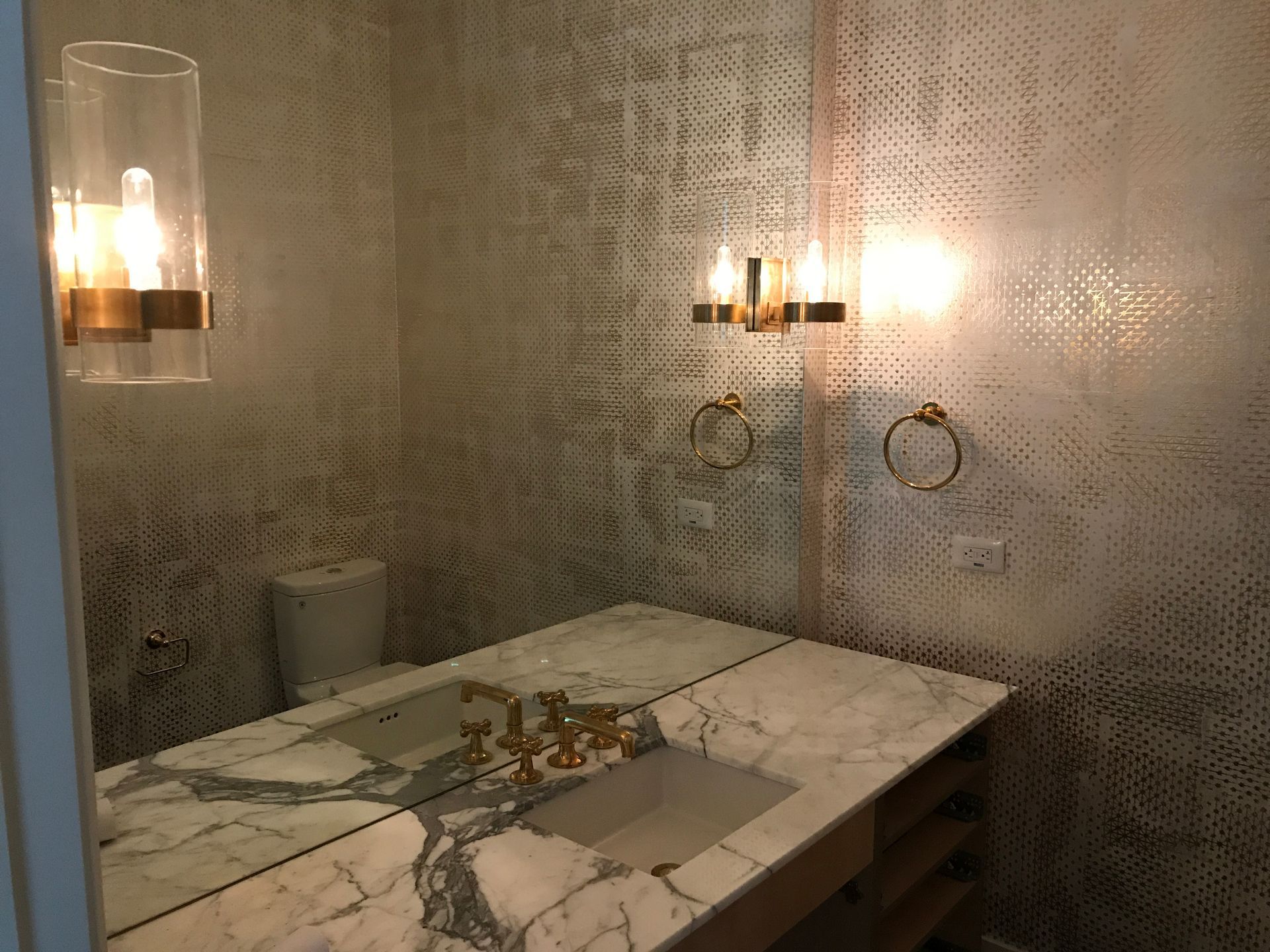 Bathroom lighting and GFCI outlet installation Austin, marble vanity with gold fixtures and patterned wallpaper