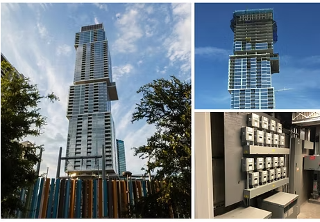 A tall modern building in Austin, TX, with glass windows and a light-colored exterior, next to a colorful fence.