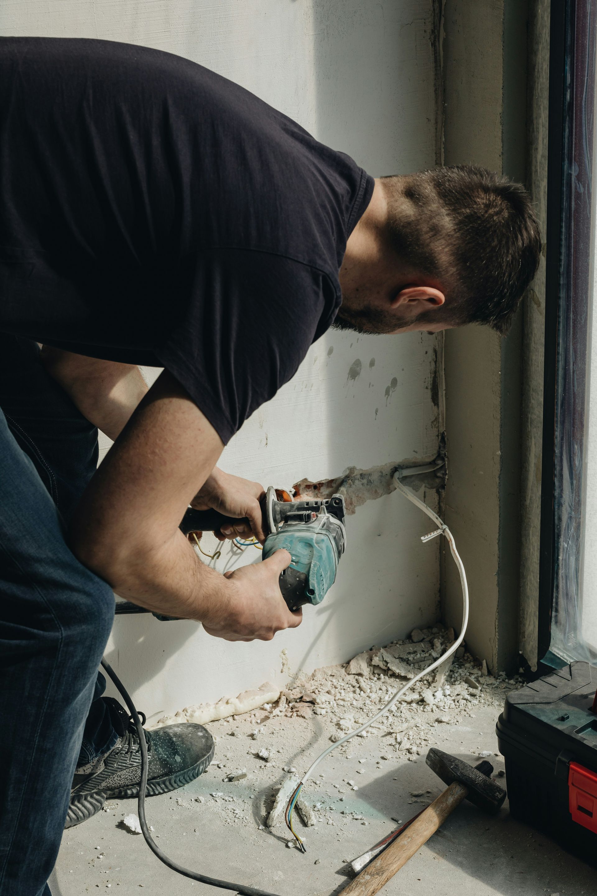 Licensed electrician Austin installing outlet and low-voltage wiring, interior wall cut-in near a window