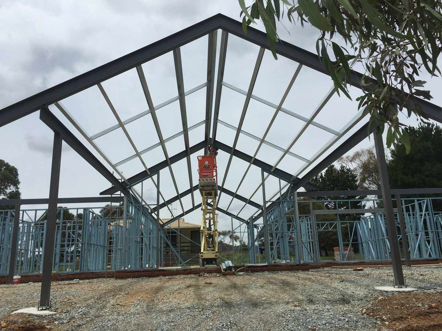 A Man on A Ladder Is Working on The Roof of A Building — Magnum Steel In Crestwood, NSW
