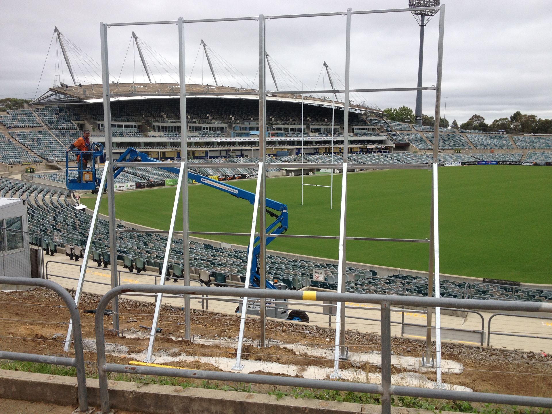 A man on a ladder stands in front of a stadium — Magnum Steel In Crestwood, NSW