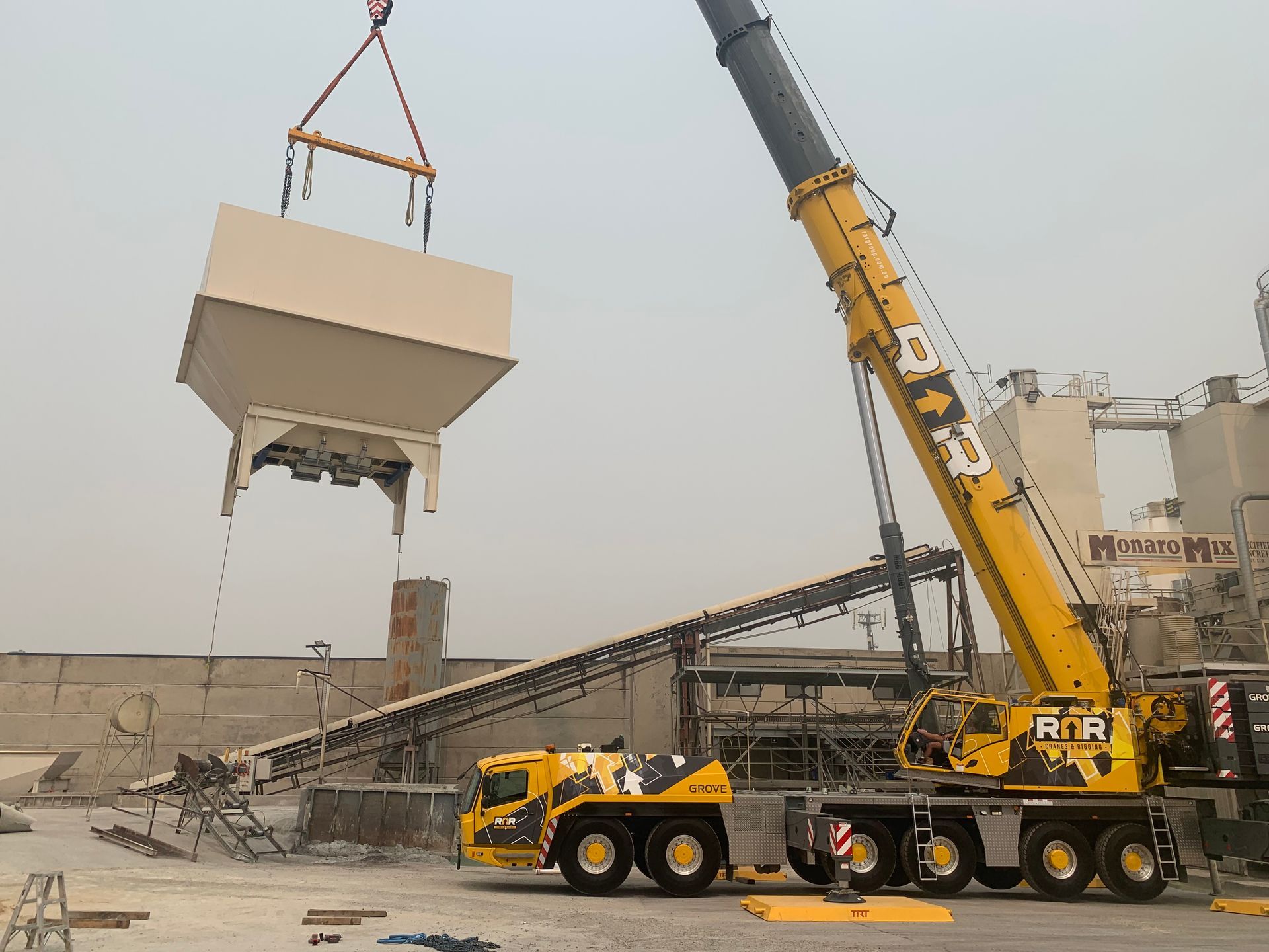 A large yellow crane is lifting a large white box in a factory — Magnum Steel In Crestwood, NSW