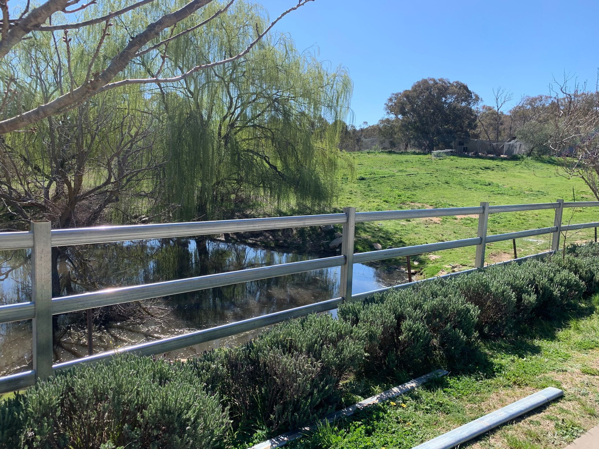 A metal fence surrounds a grassy field next to a river — Magnum Steel In Crestwood, NSW
