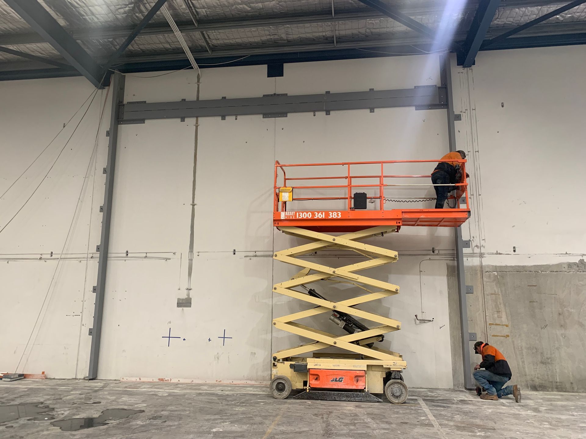 A man is working on a scissor lift in a warehouse — Magnum Steel In Crestwood, NSW