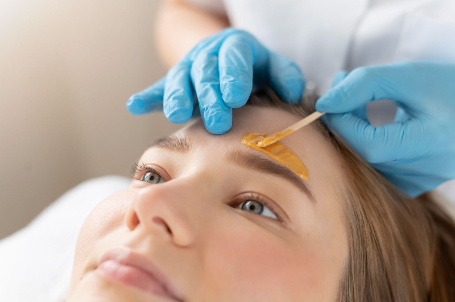 A woman is getting her eyebrows waxed in a beauty salon.