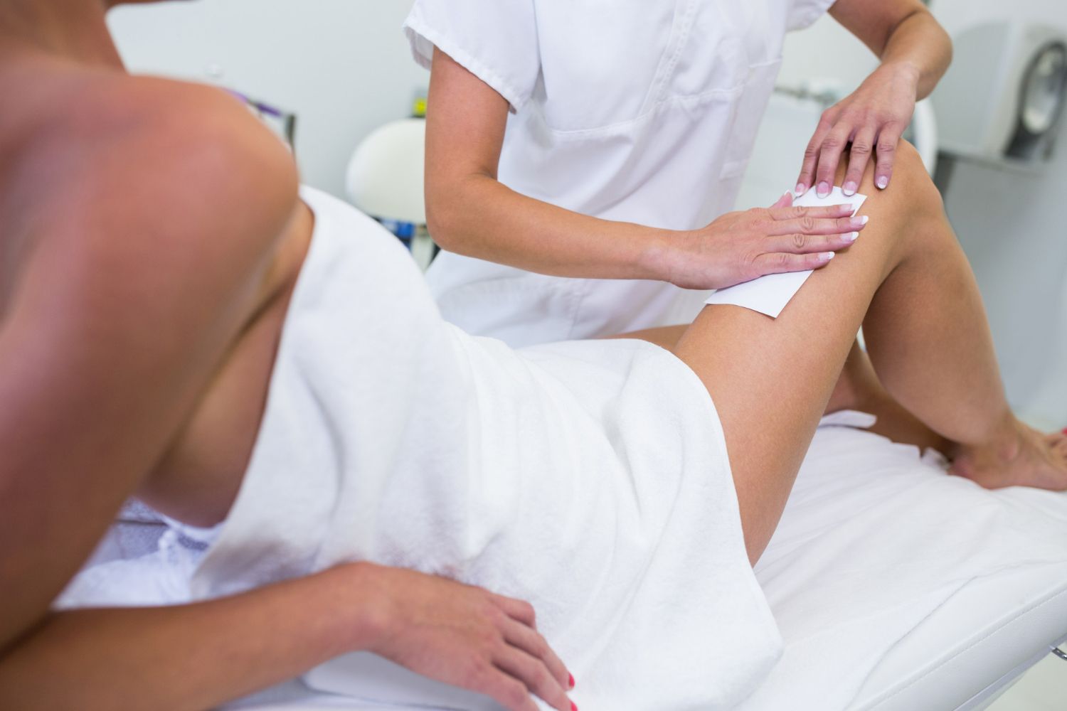 A woman is getting her legs waxed by a woman in a spa.