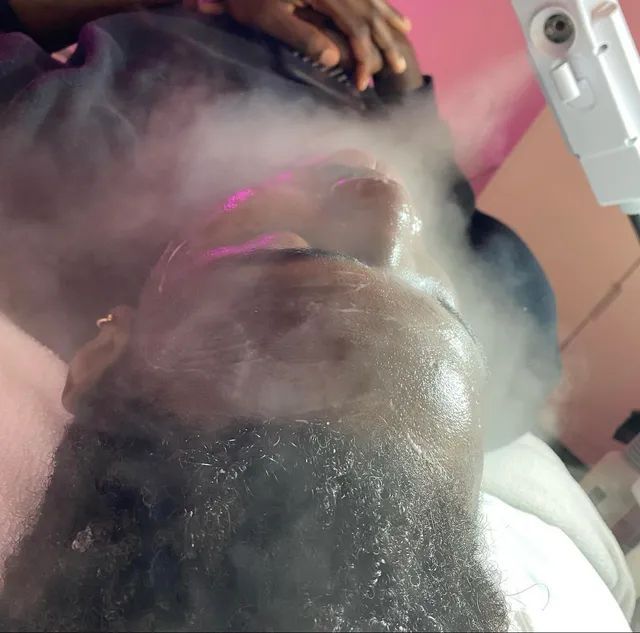 Person receiving a facial treatment with steam covering their face at a spa.