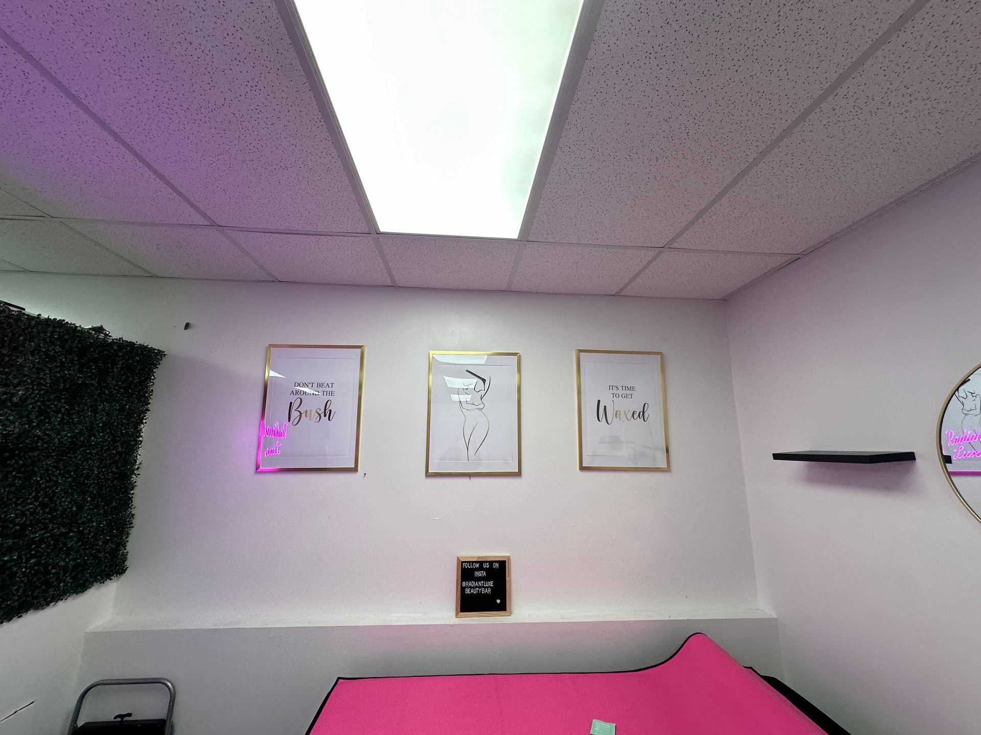 A room with a pink bed and three paintings on the wall.