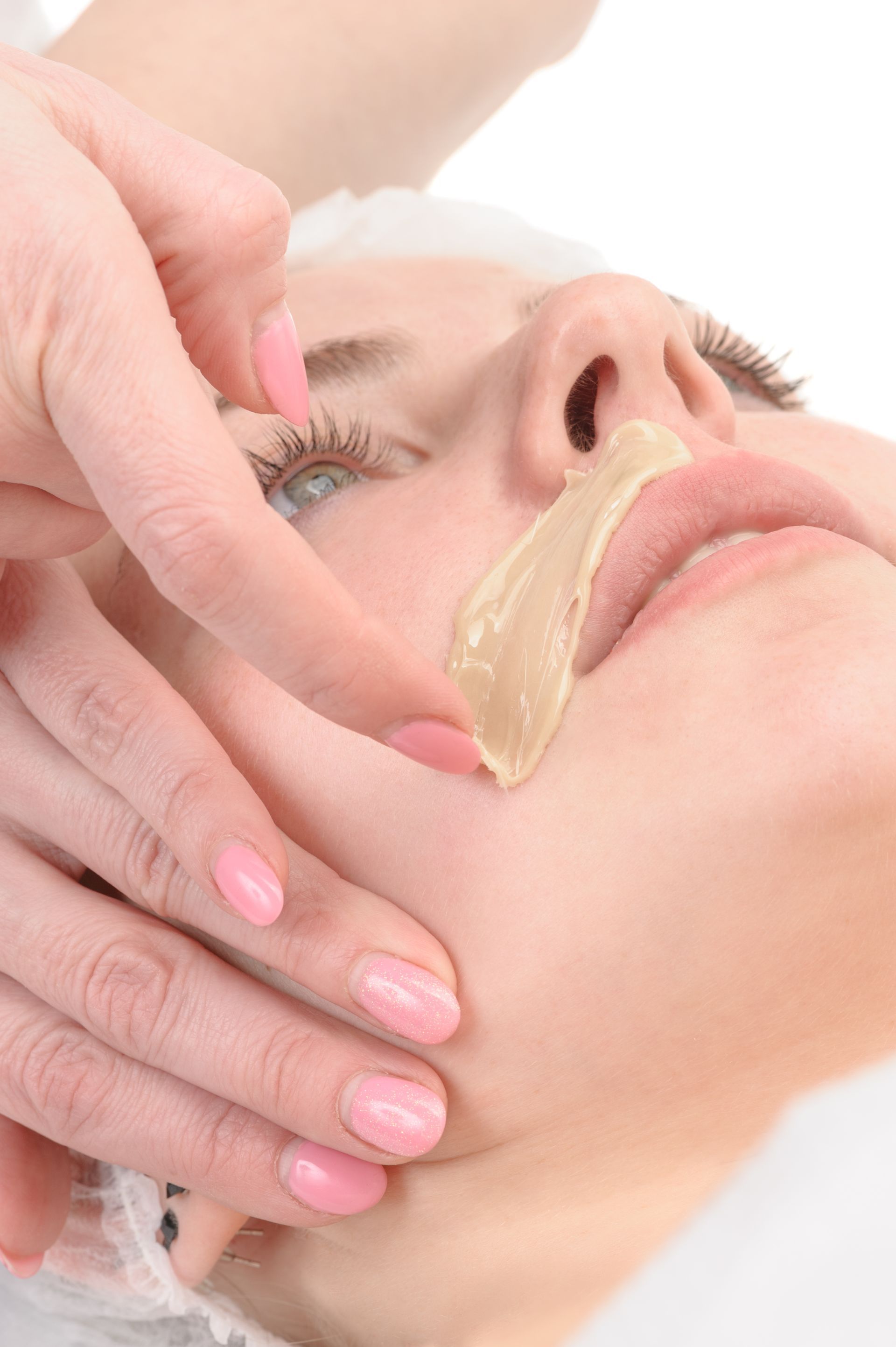 A woman is getting a wax treatment on her face.