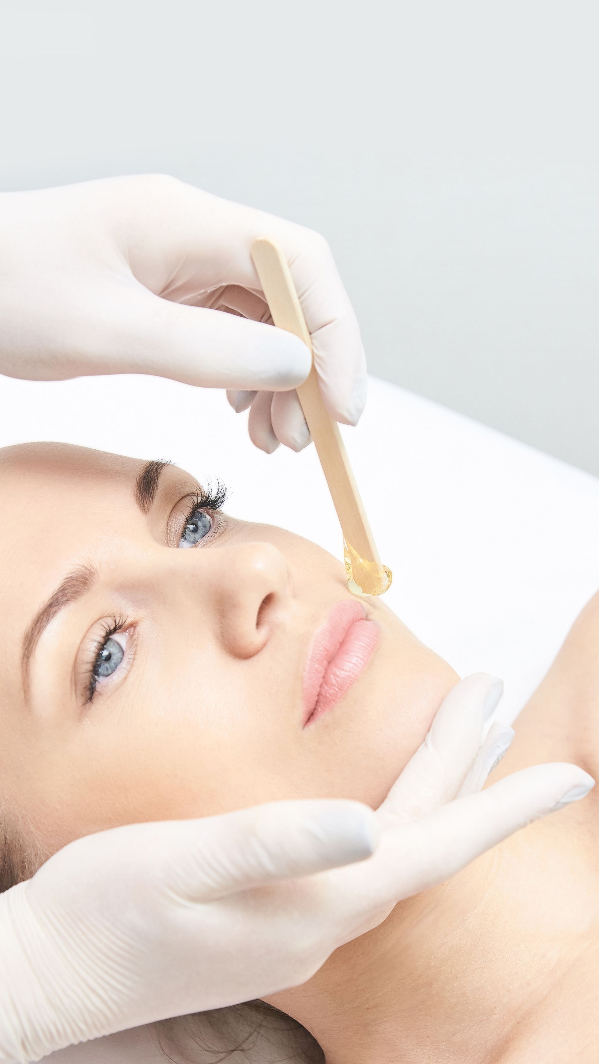 A woman is getting a waxing treatment on her face.