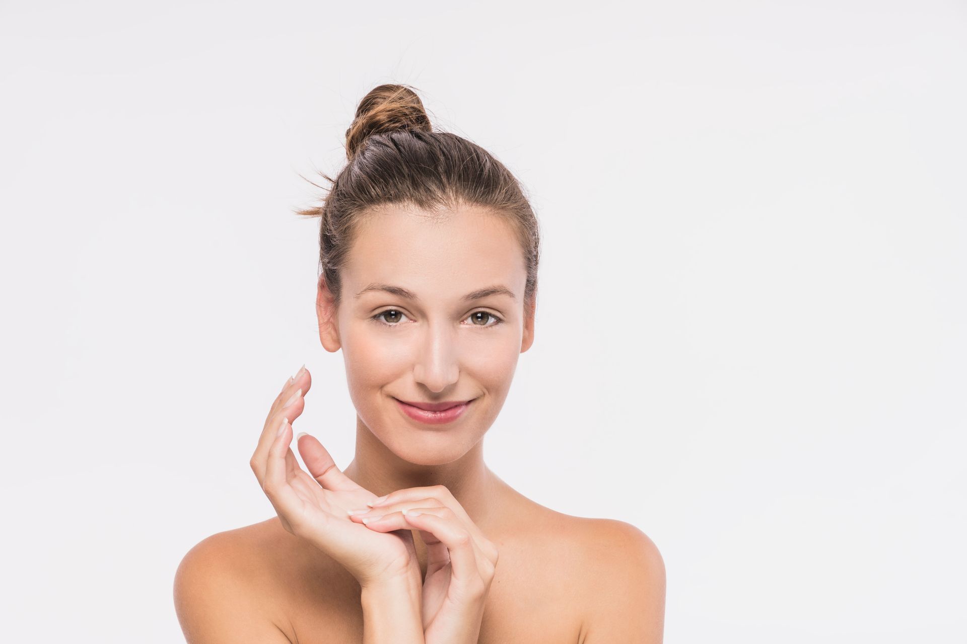 A woman is smiling and touching her face with her hands.