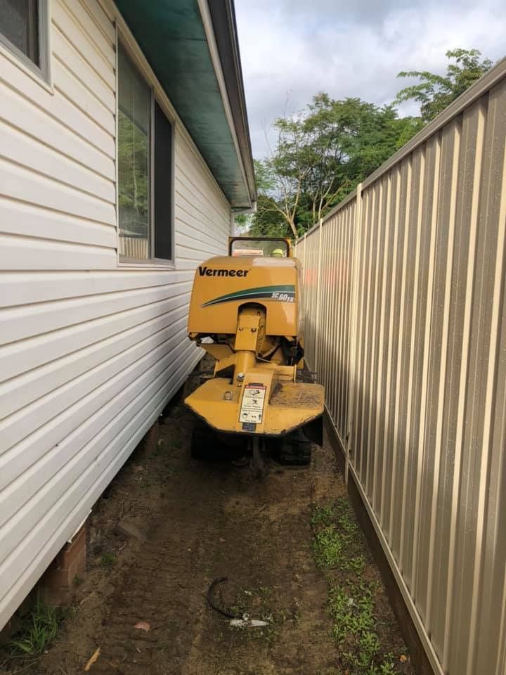 A Yellow Machine Is Parked On The Side Of A House Next To A Fence — All Area Tree Service Pty Ltd In Fountaindale, NSW