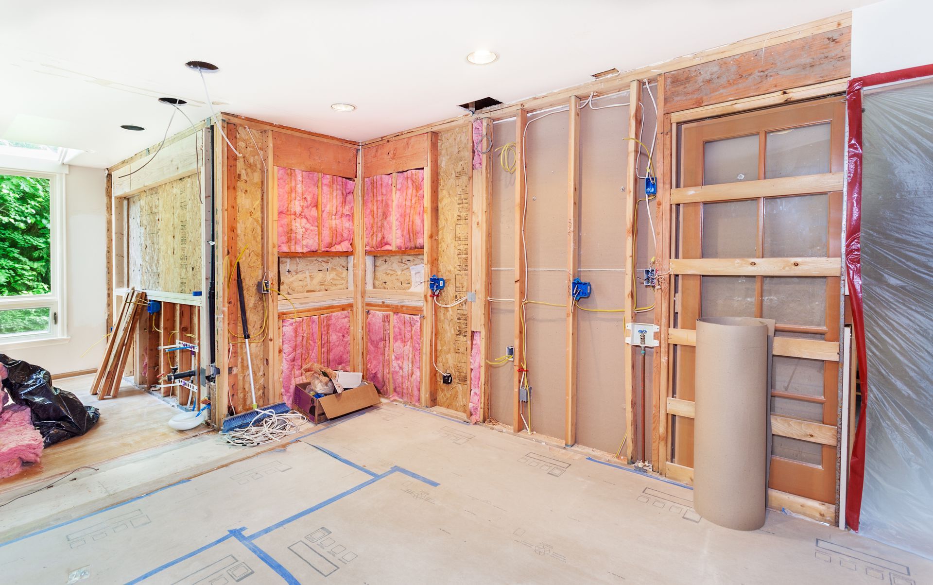 Interior room under renovation with exposed wall studs, insulation, and unfinished flooring.