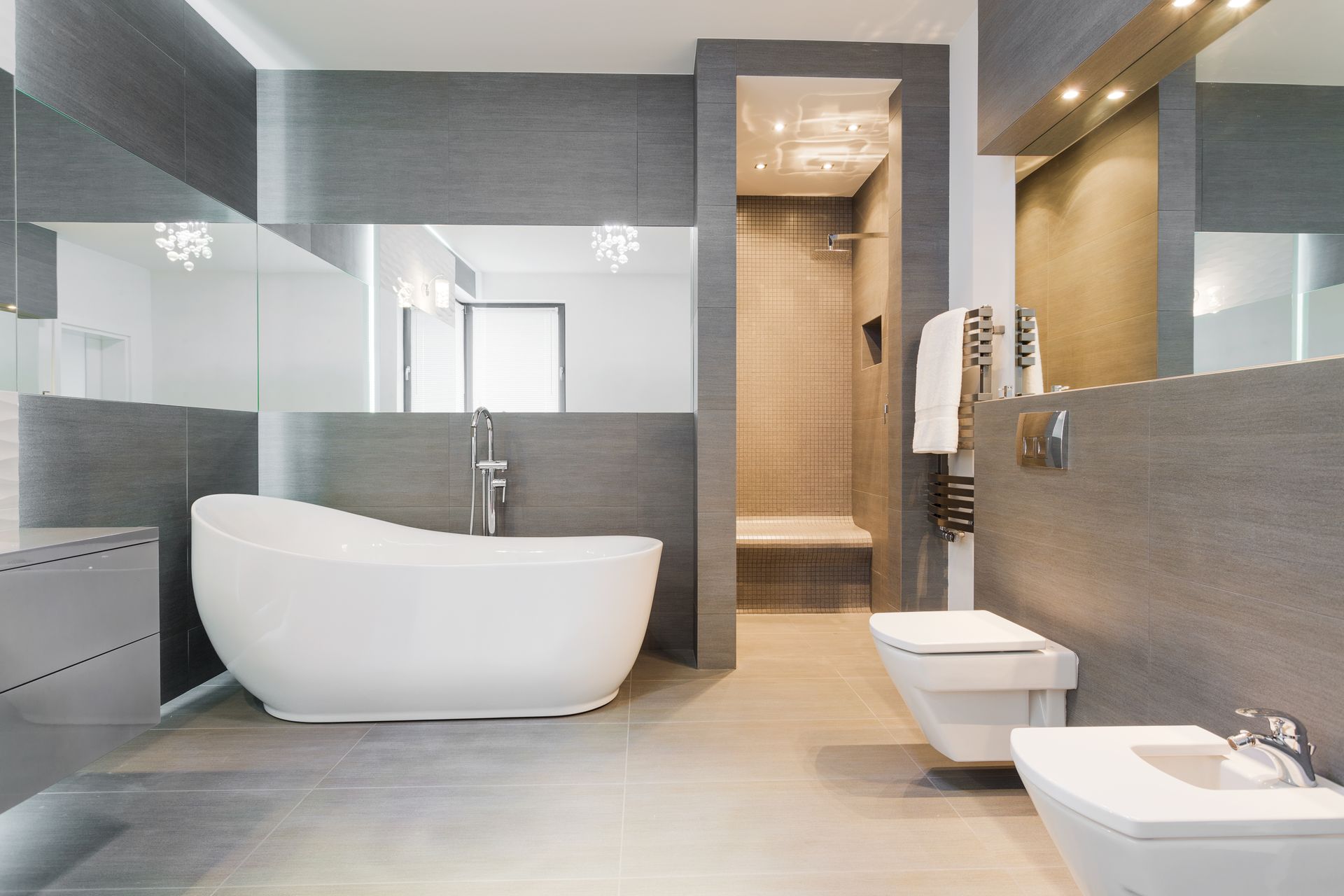 Modern gray bathroom with freestanding tub, walk-in shower, and wall-mounted toilet Modern gray bathroom with freestanding tub, walk-in shower, and wall-mounted toilet