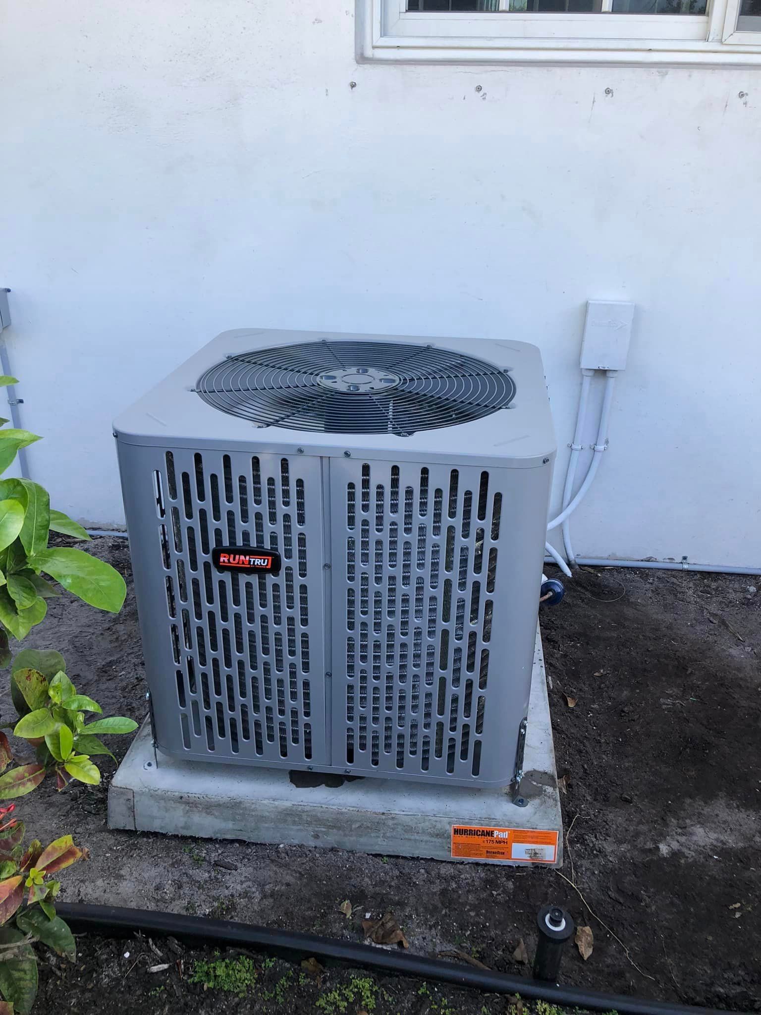 An air conditioner is sitting on the side of a building next to a window.