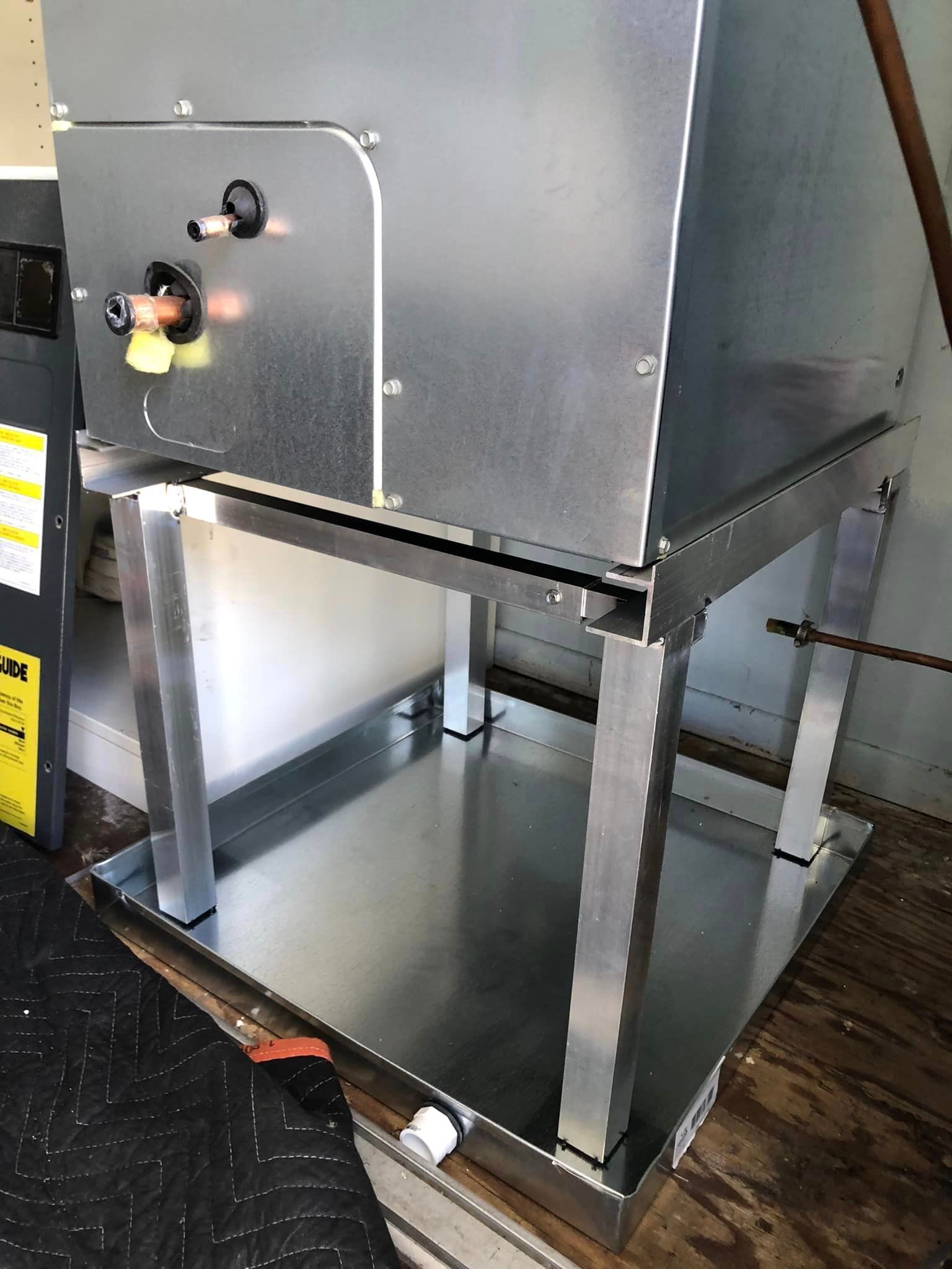 A metal box is sitting on top of a metal tray on a wooden floor.