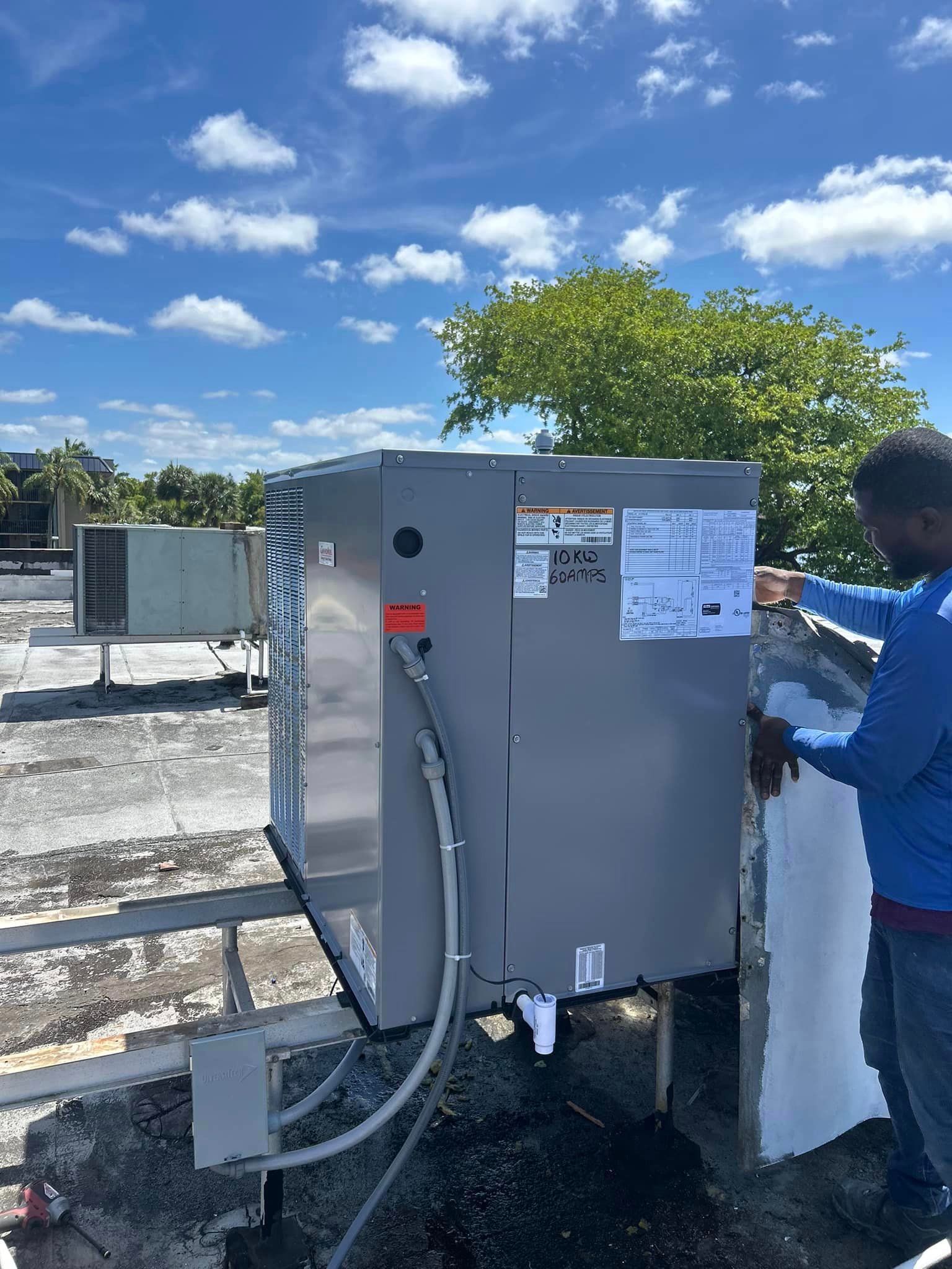 A man is working on an air conditioner on top of a roof.
