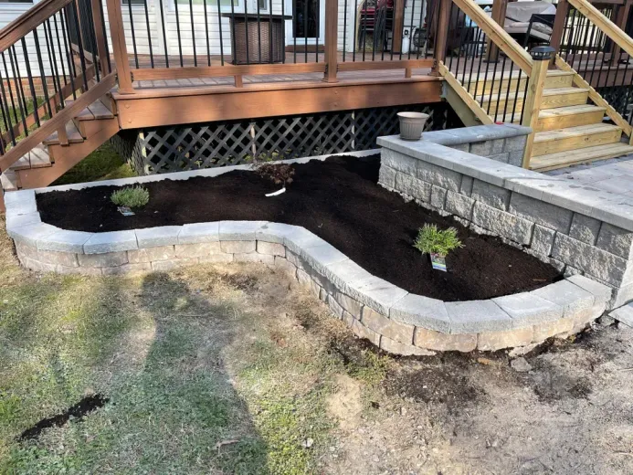 A planter is being built in the backyard next to a deck.