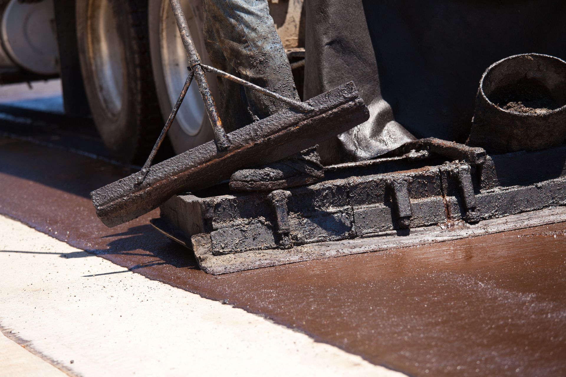 Road worker resurfacing street with hot tar.